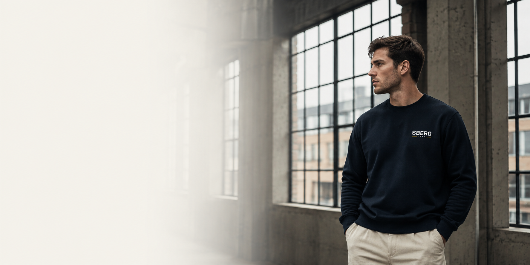 Man in donker navy SBERG sweater in een industriële loft