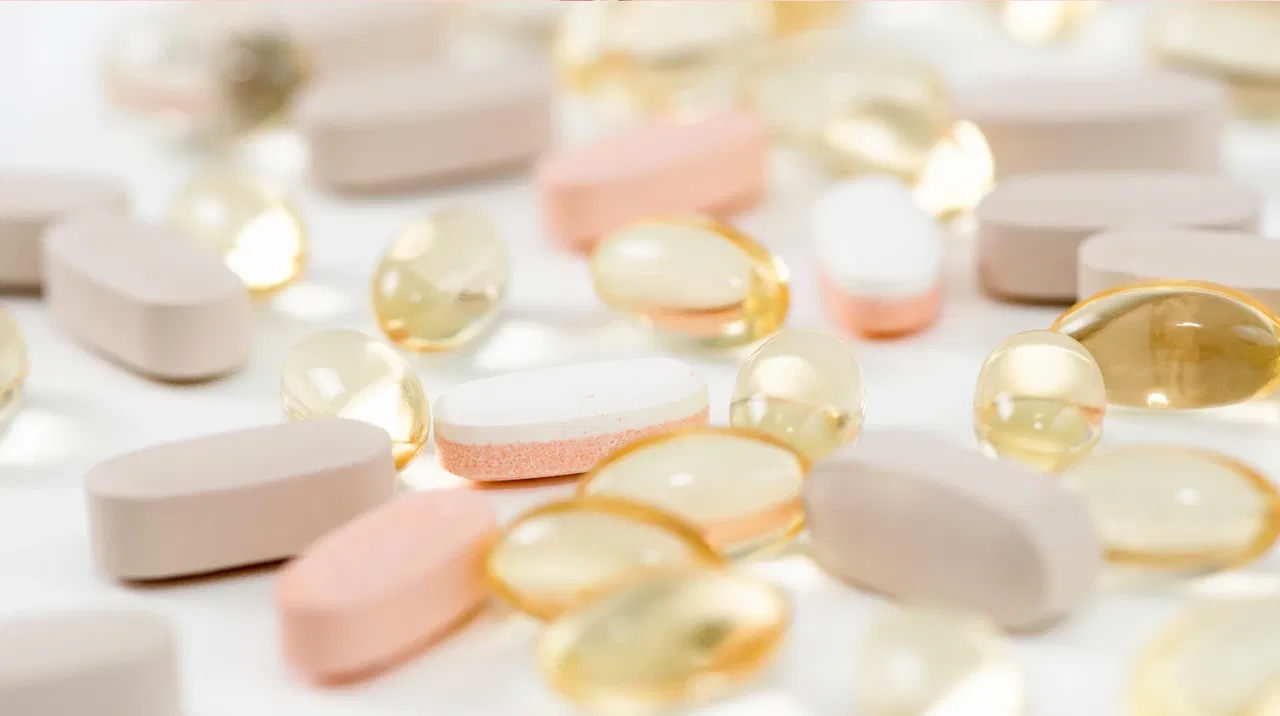 Various pills and capsules scattered on a white surface.