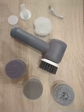 Photo envoyée par un client : la brosse de nettoyage déballée sur un parquet, entourée de ses têtes de brosse et de son câble de recharge