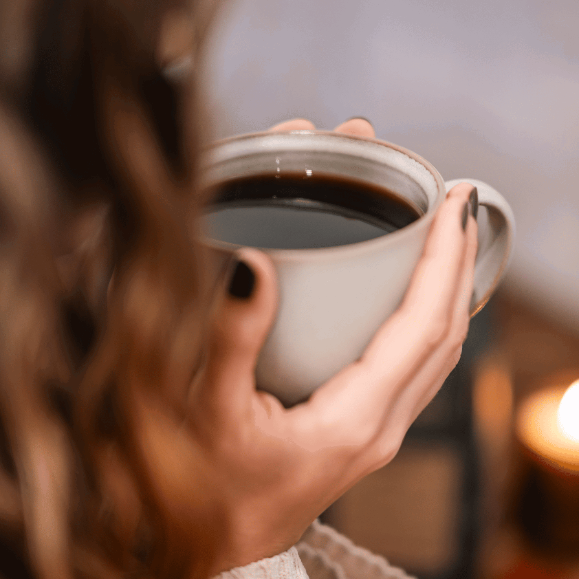 Freshly roasted coffee beans and a cup of coffee on dark slate with cinnamon and orange peel