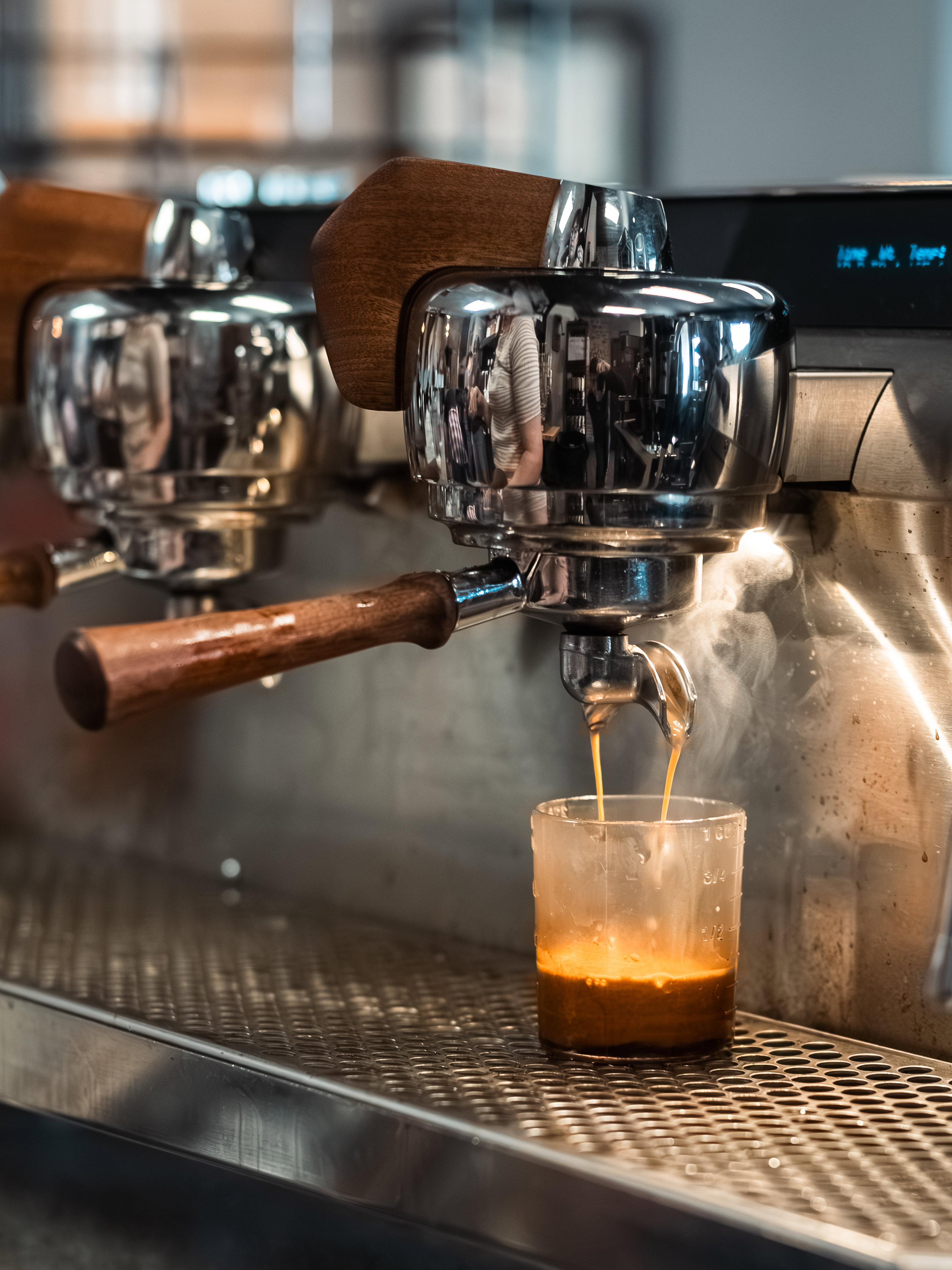 Espresso pouring from a bottomless portafilter into a glass cup with thick golden crema