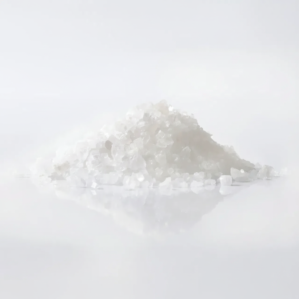 Pile of sodium chloride crystals on a white reflective backgro