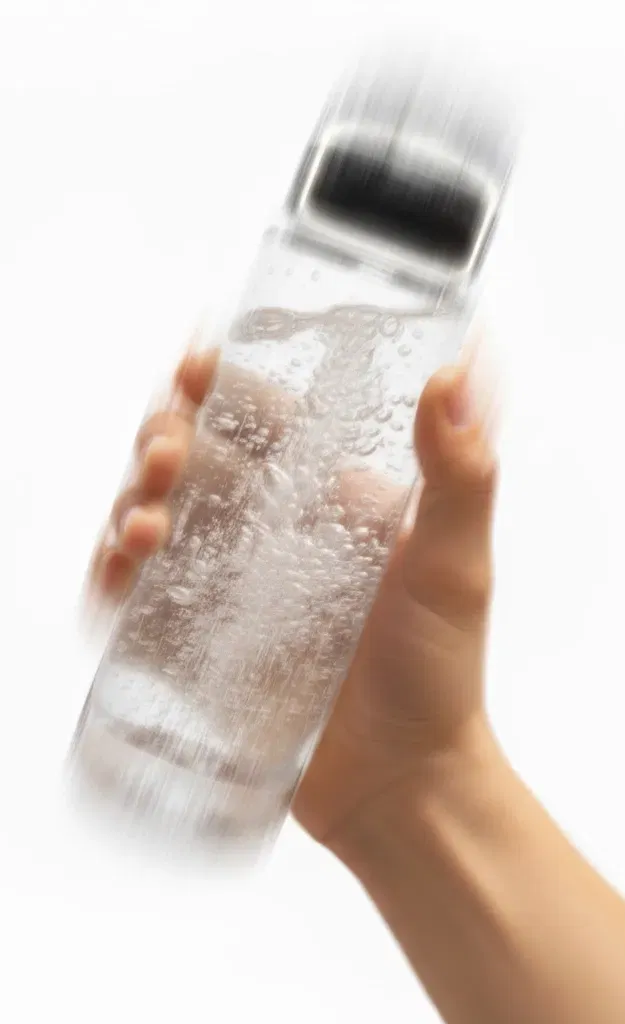 Hand holding a clear bottle with Supra creatine and electrolyte drinks inside against a white background.
