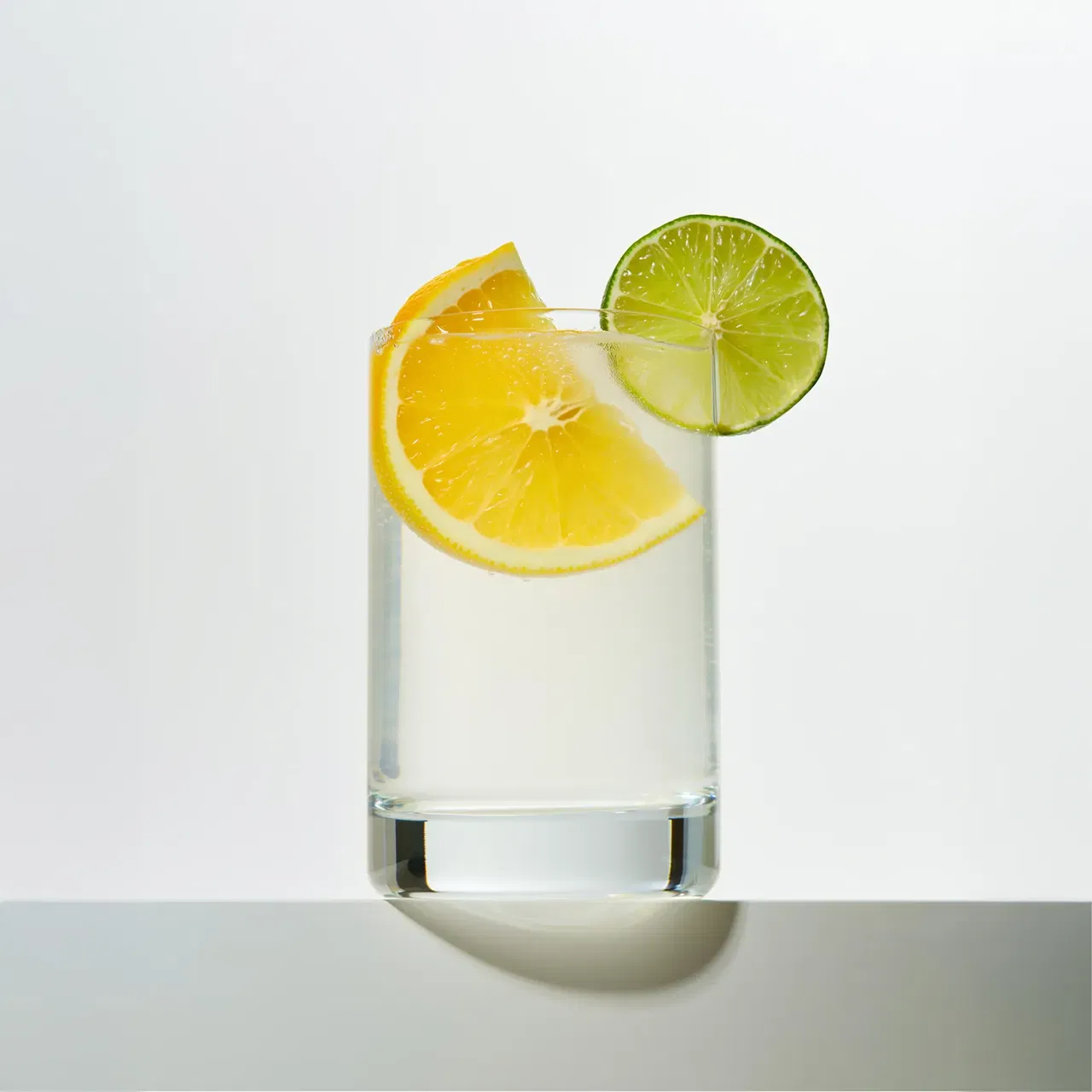 Glass of Supra Creatine + electrolytes with a lemon wedge inside and a lime slice on the rim.