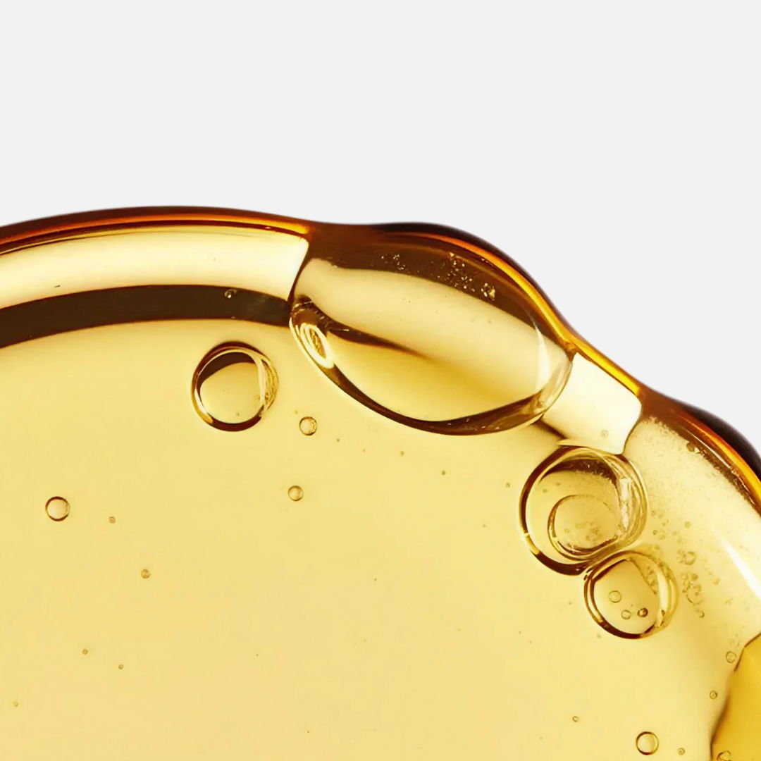 Detalle de un líquido dorado con burbujas sobre fondo claro