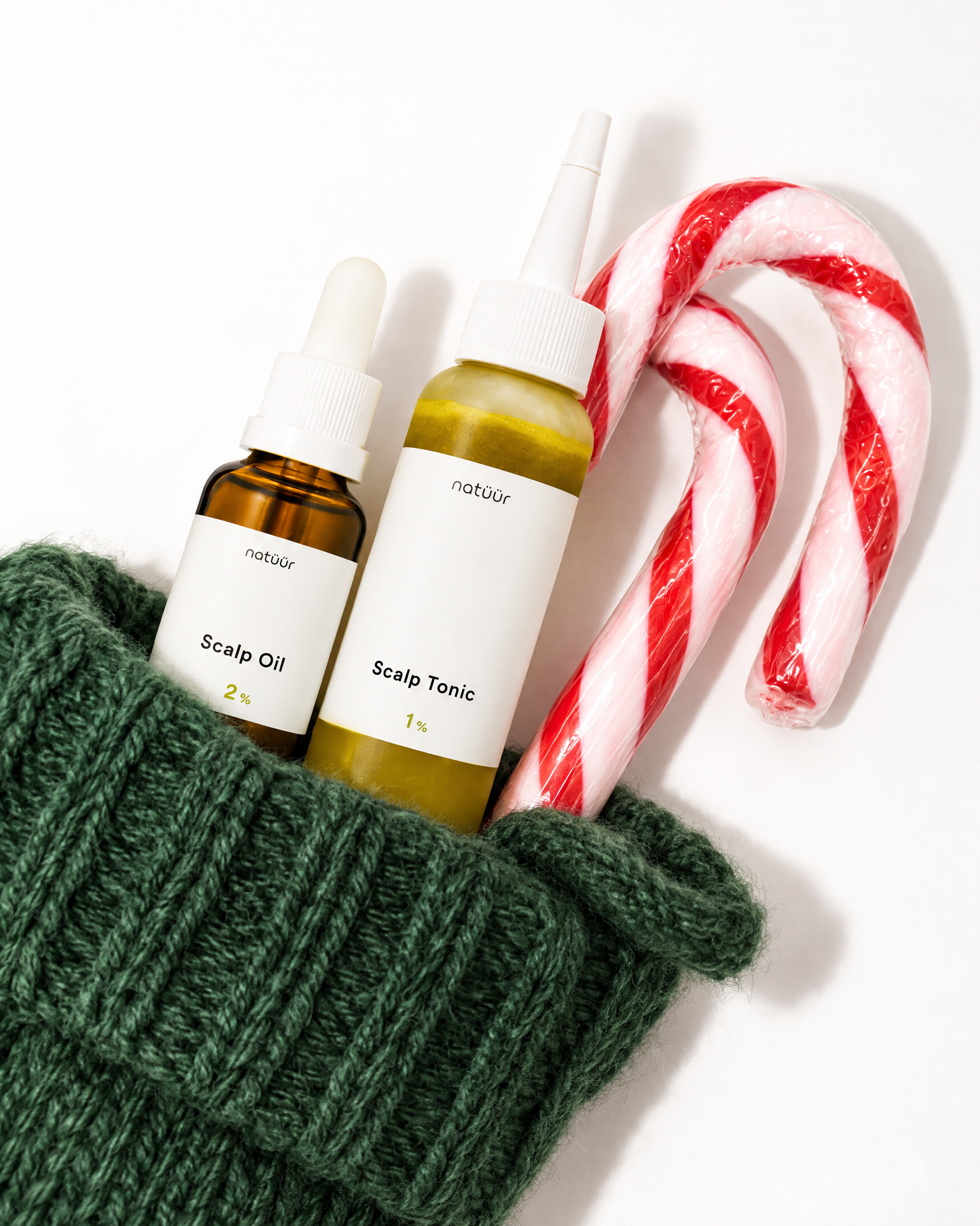 natüür Scalp Oil und Scalp Tonic in einem grünen, gestrickten Weihnachtsstrumpf mit Zuckerstange