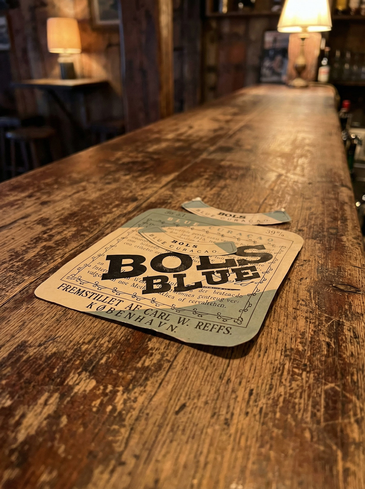 Two vintage Bols Blue labels placed on a worn wooden bar surface in a dimly lit room
