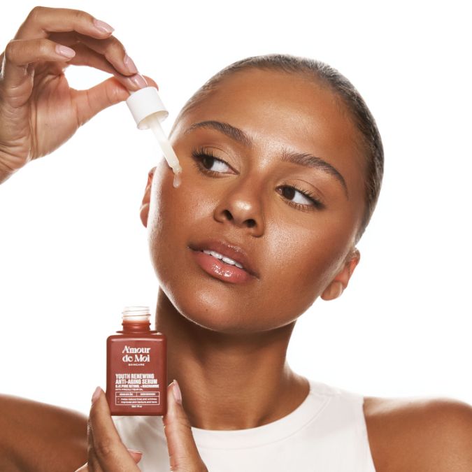 Woman in a hair towel gently massaging serum into her cheek