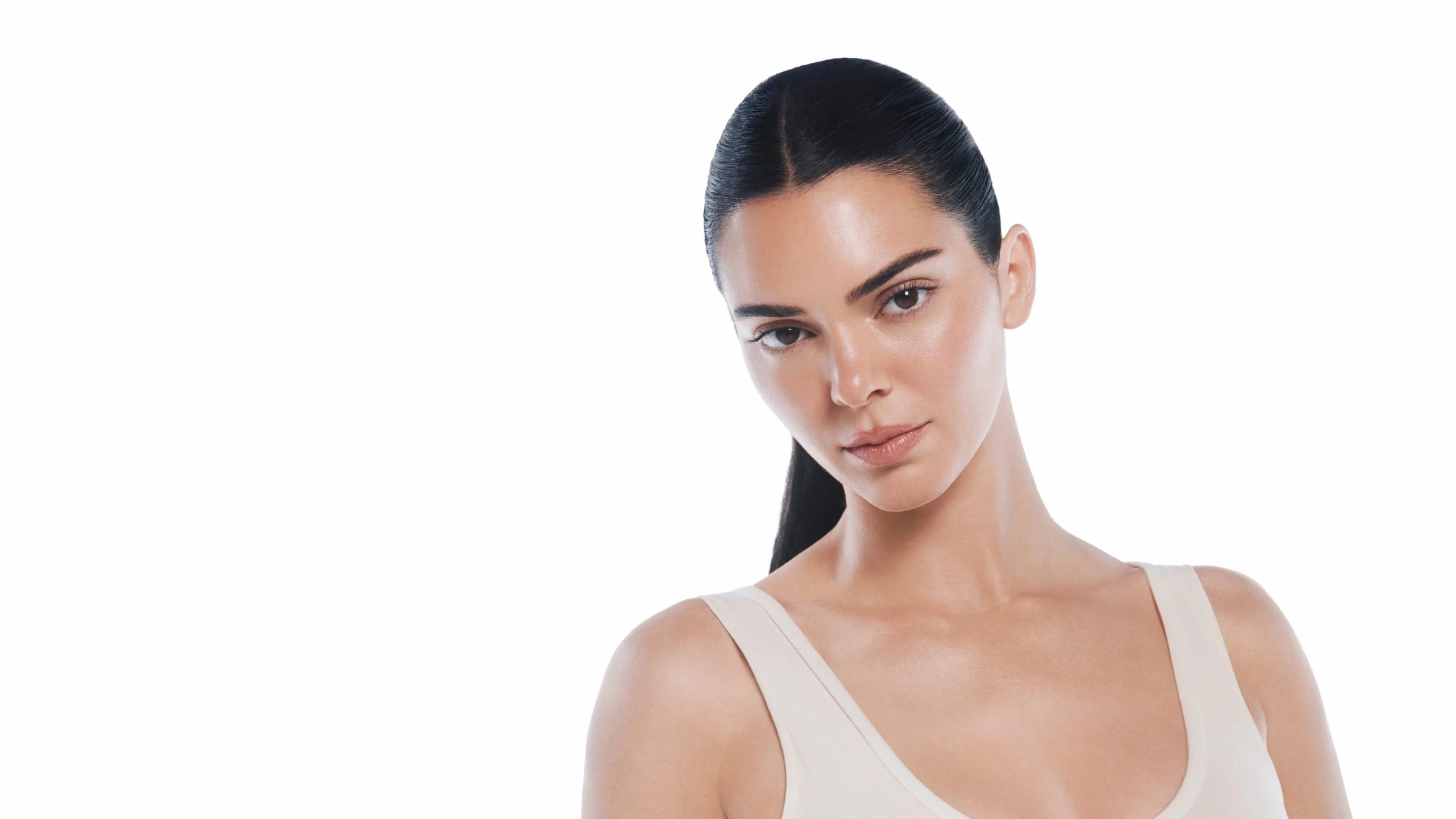 Mulher sorridente com pele luminosa a segurar um creme K-Beauty