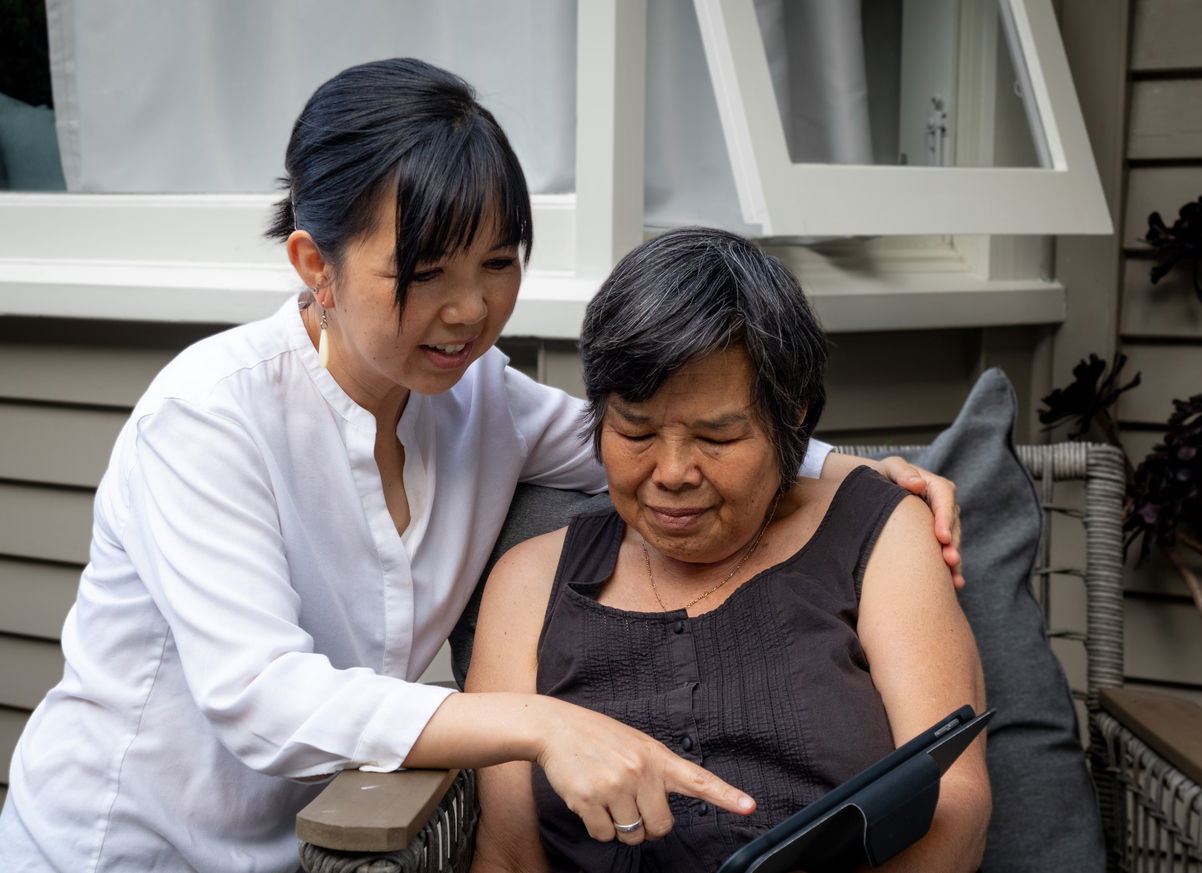 Mom and her adult daughter are looking at digital smart clock display outside
