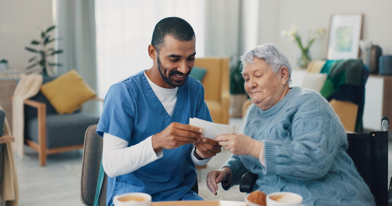 Caregiver shows a photo to an elderly woman in a wheelchair in memory care.