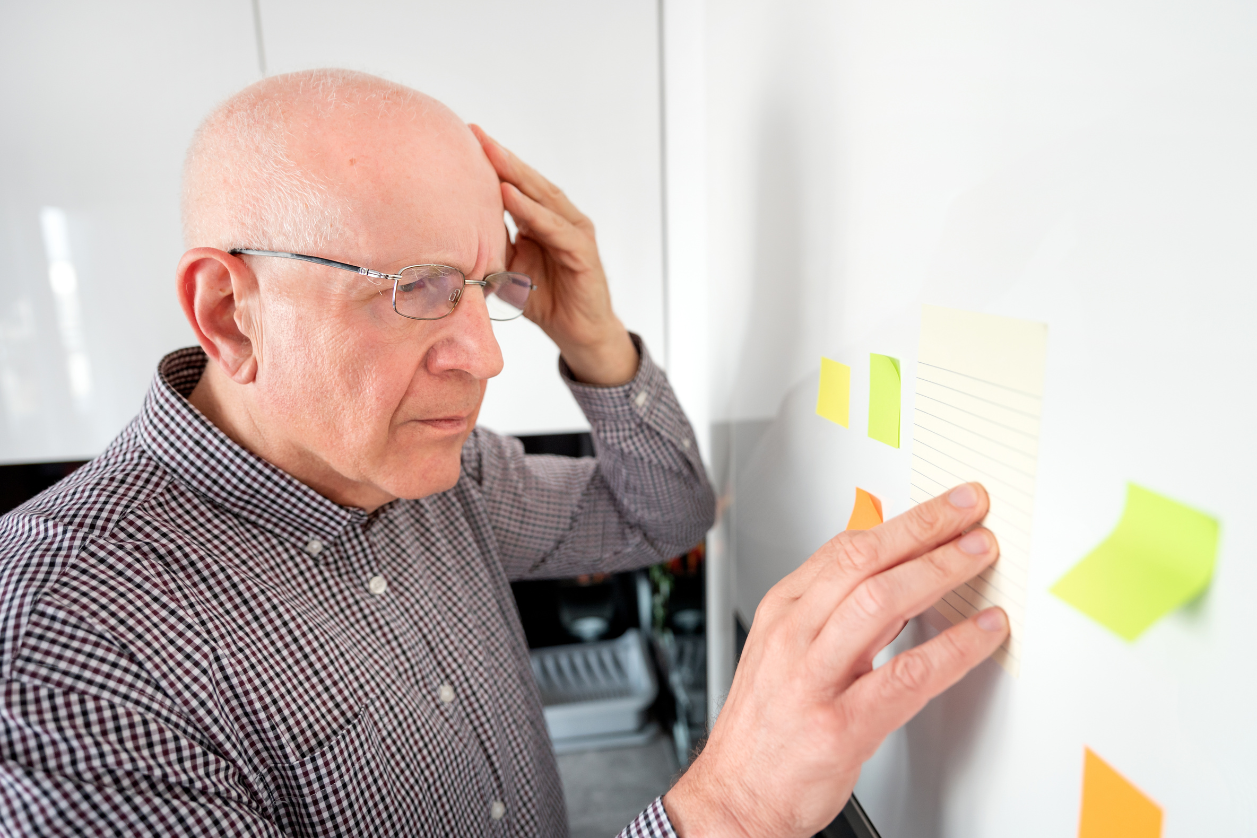 Person with dementia looking at whiteboard with sticky notes on it.