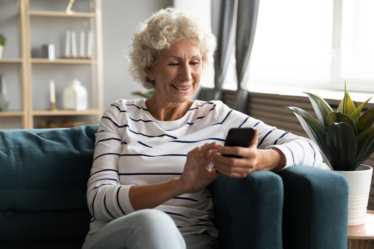 Dementia patient in a living room using tech gadgets to make life easier.