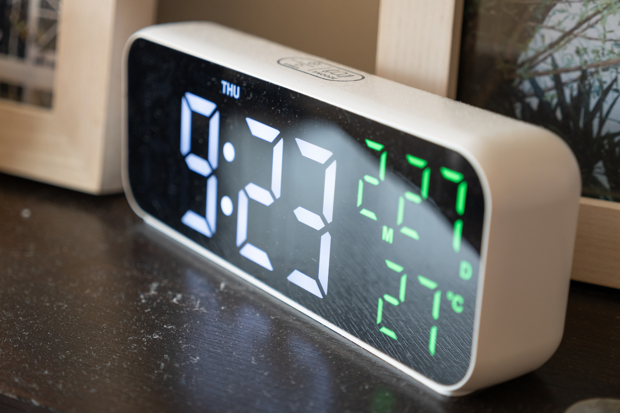 Dementia clock sitting on a counter being compared to a digital reminder board.