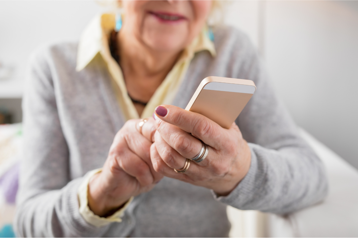 Older adult is holding a mobile phone looking at apps for staying connected