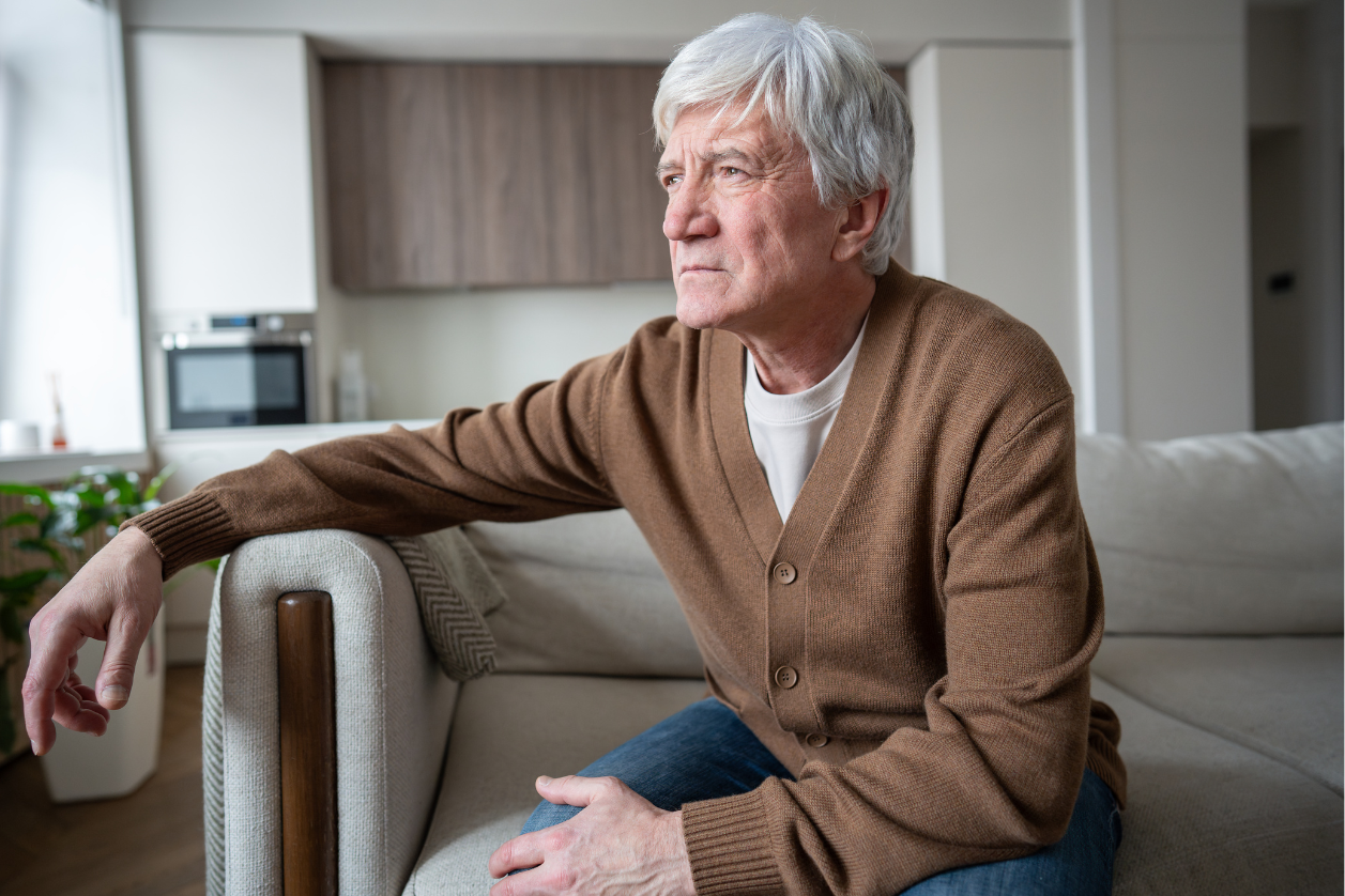 Older adult with dementia sitting on a couch asking the same question over and over agai