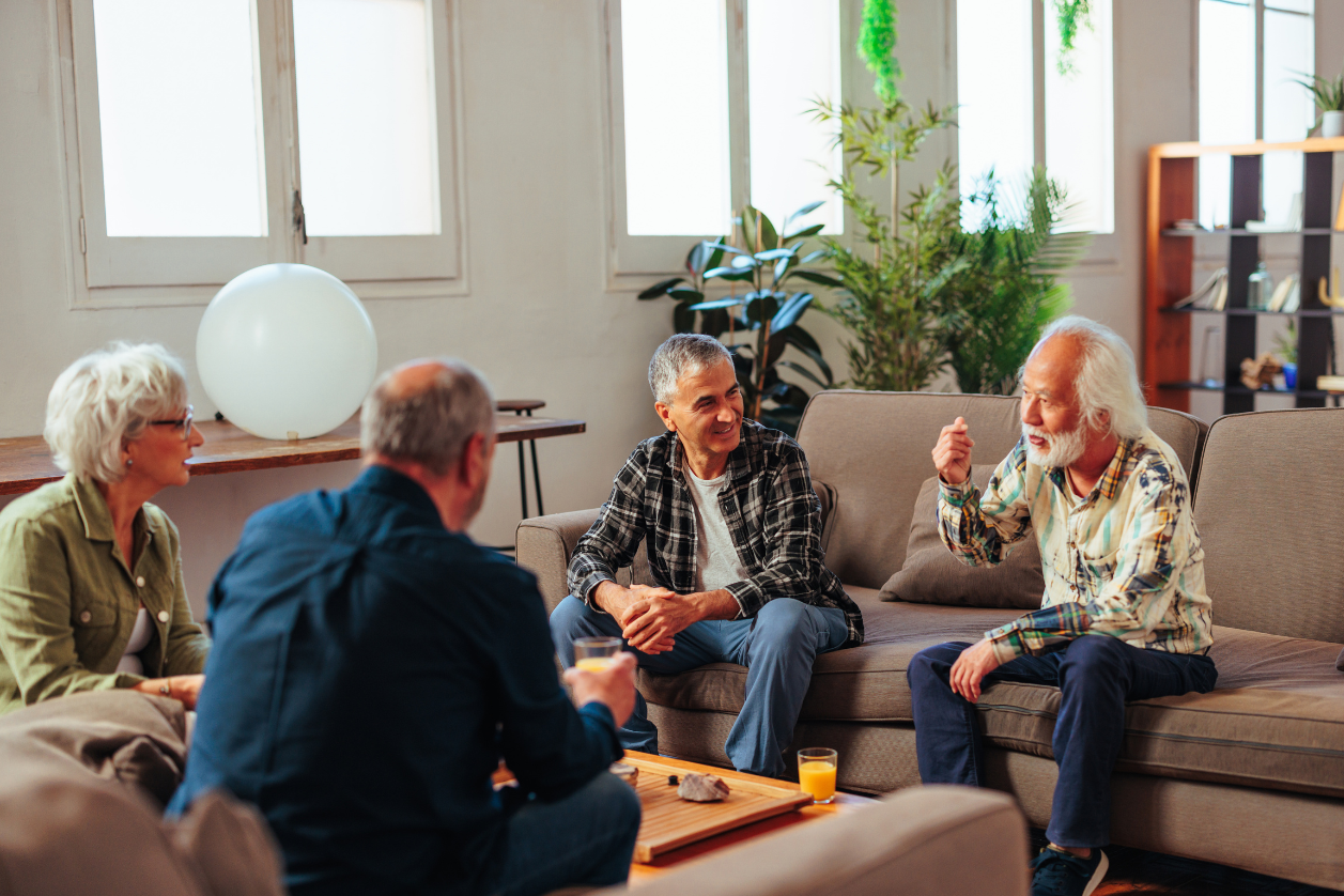 Older adults in a living room talking about a memory board for dementia.