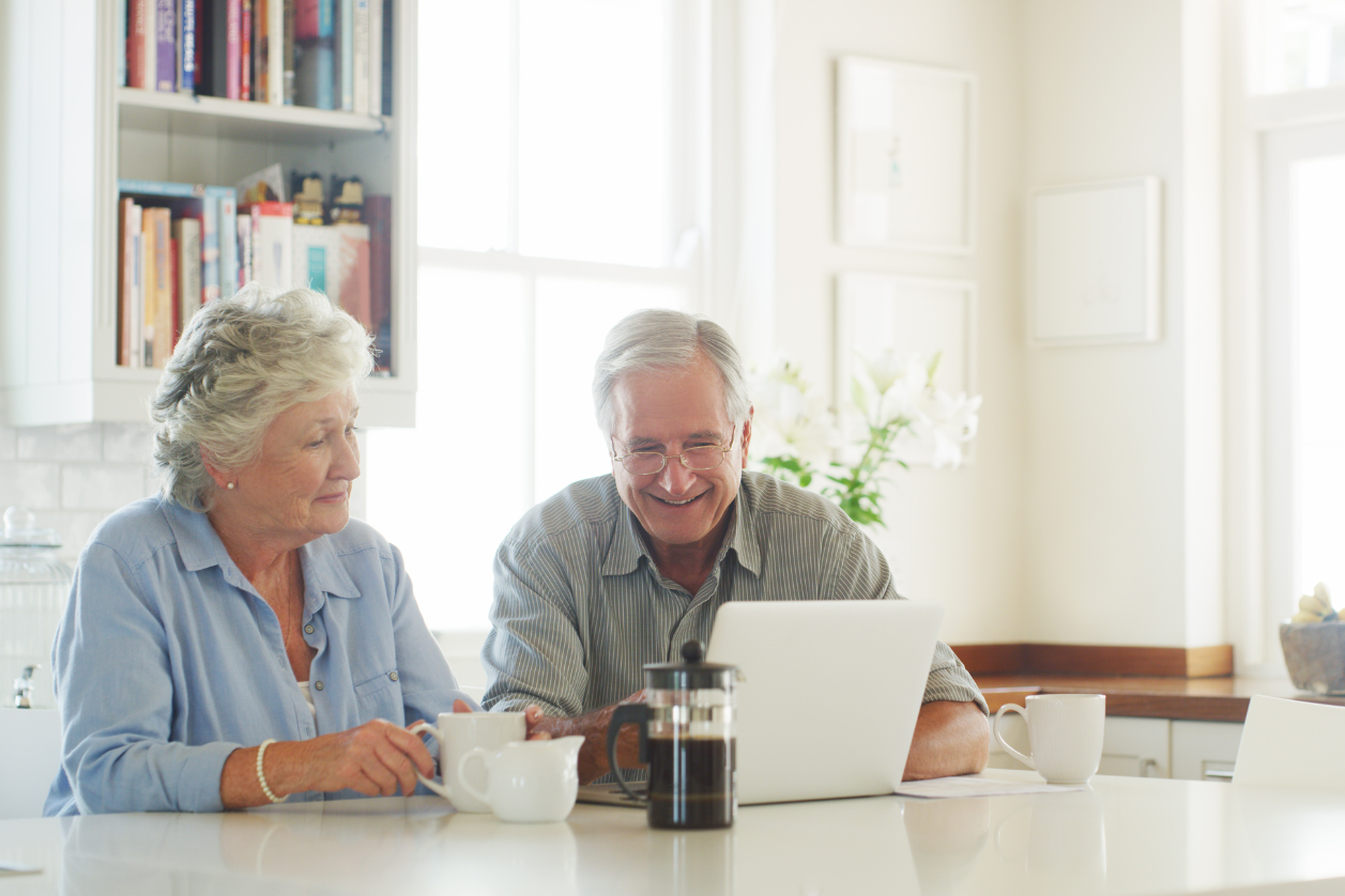 Older adults aging in place looking at computer in dining room.