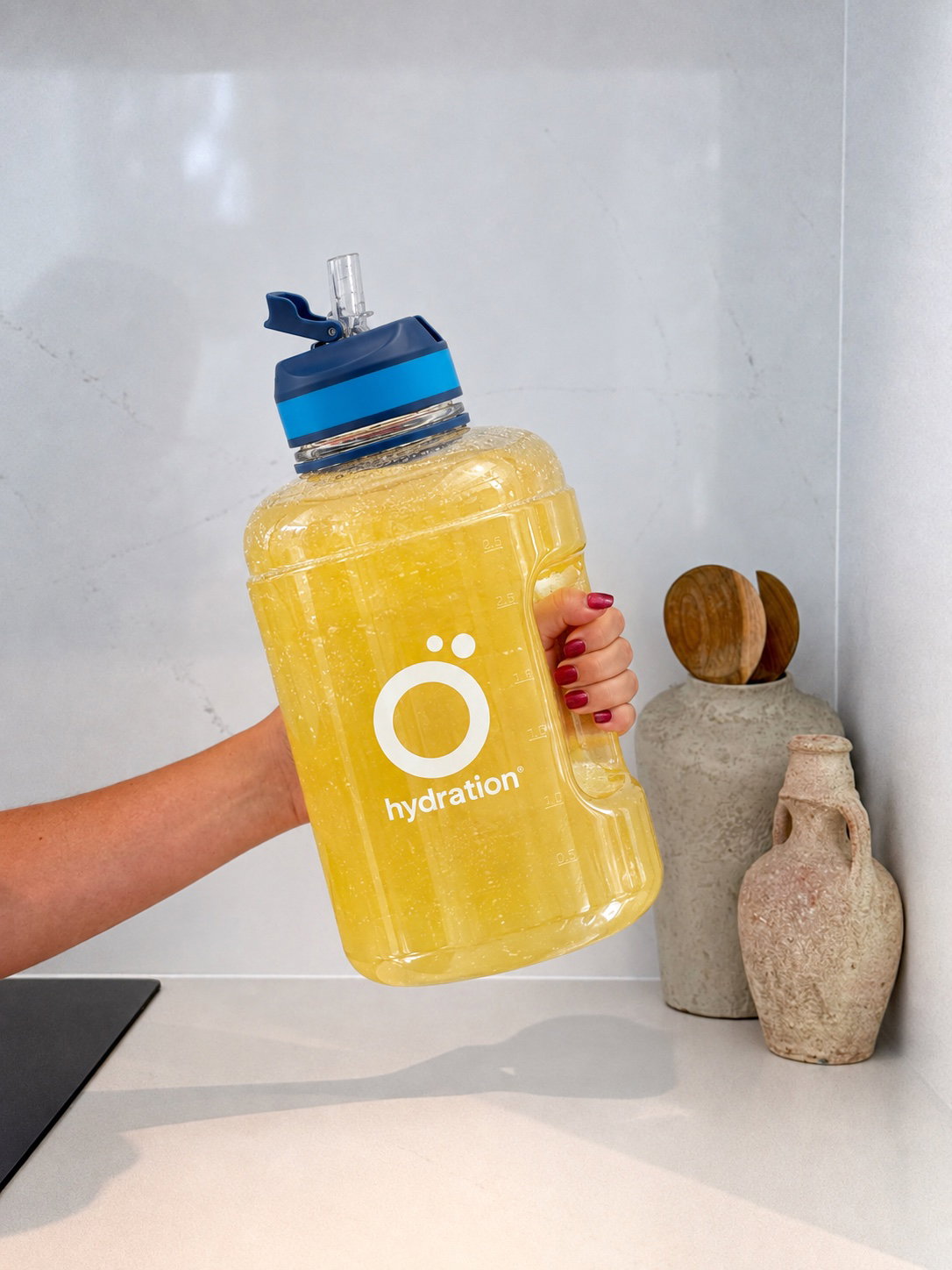 Des mains secouant la bouteille Ö d’eau aromatisée