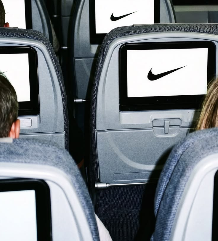 Nike campaign image: rows of aircraft seatback screens, each showing a black Swoosh on a white screen