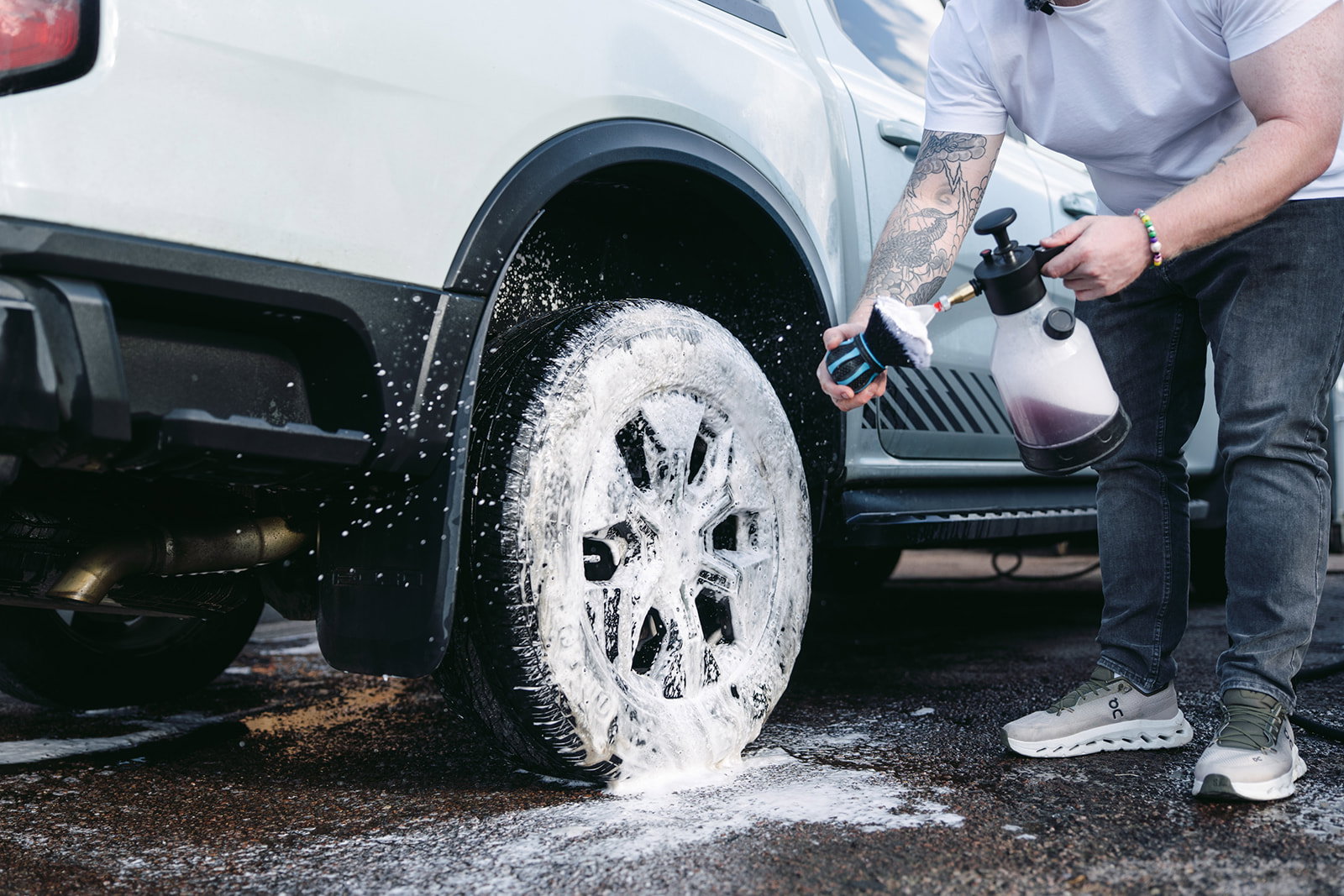 Hydro Orb Brush being loaded with snow foam next to a foamed alloy wheel