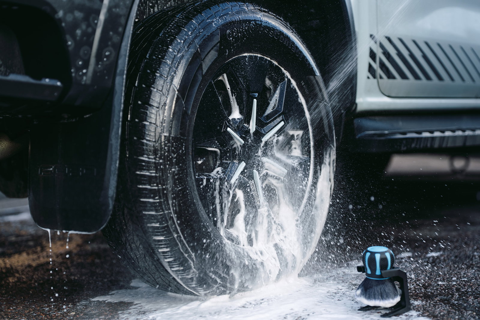 Alloy wheel being rinsed with the Hydro Orb Brush waiting on its stand