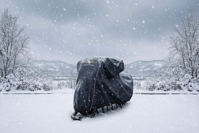 A covered motorcycle in falling snow