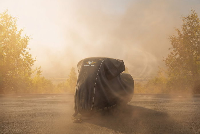 A covered motorcycle in blowing dust