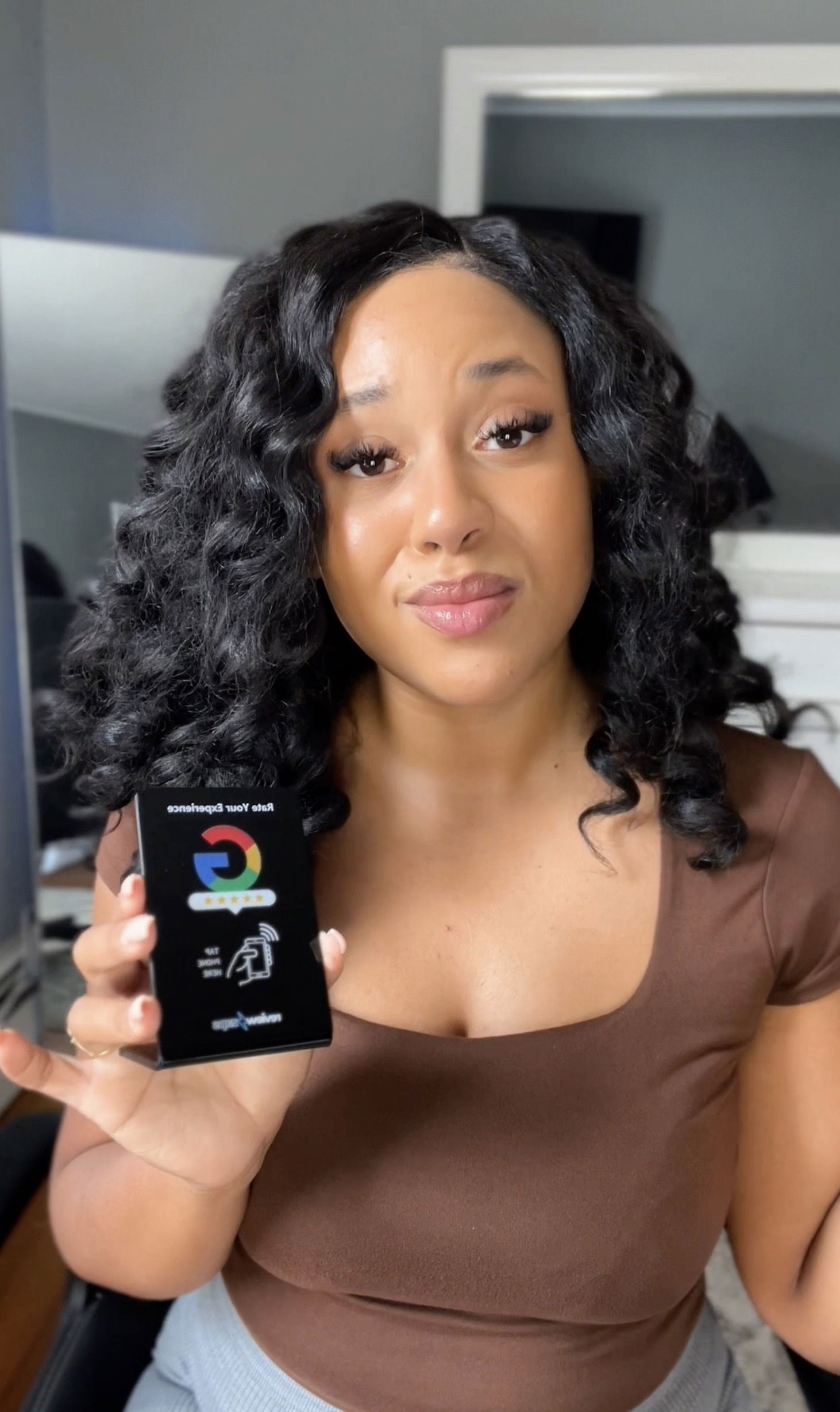 Yolanda Reyes, owner of Bloom Nail Salon, holding a Review Zaps NFC review card