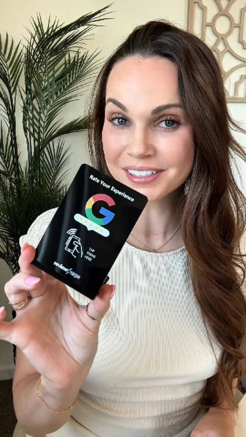 Brook Skylers, owner of Glow Salon, holding a Review Zaps NFC review stand