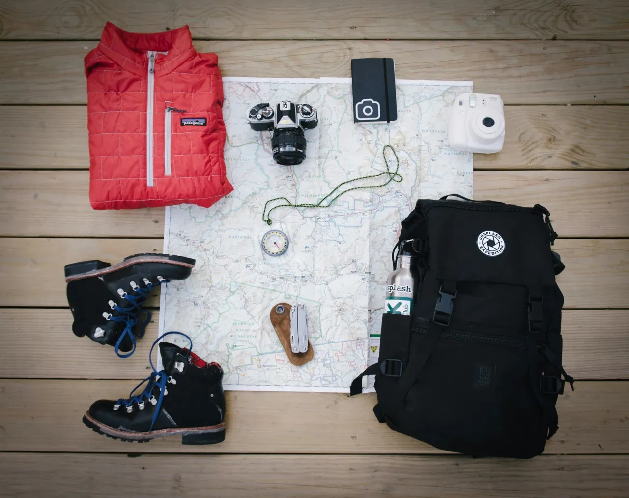map, outdoor clothing, and compass laid out on the floor