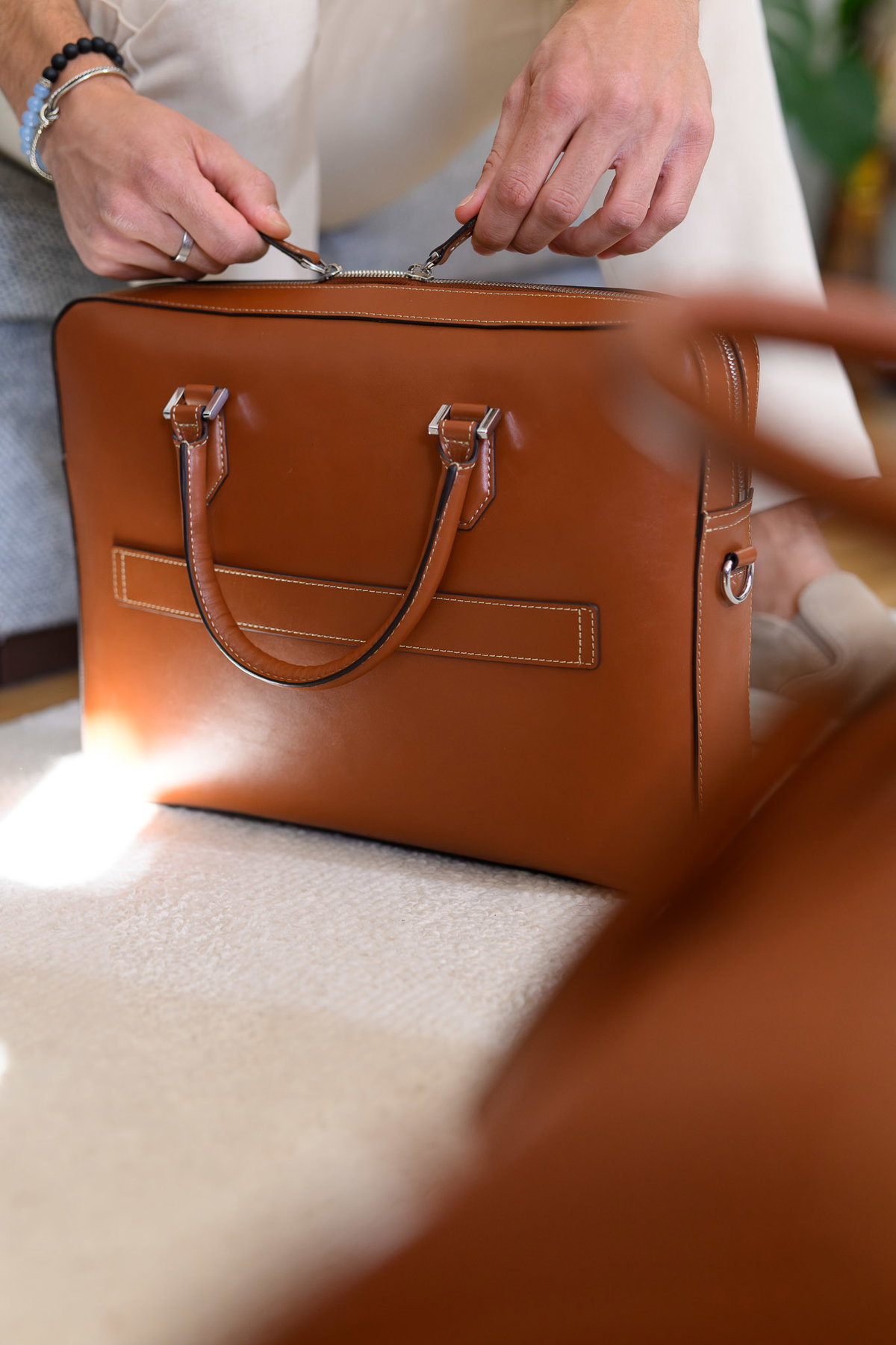 Hands zipping open a cognac leather Urban briefcase