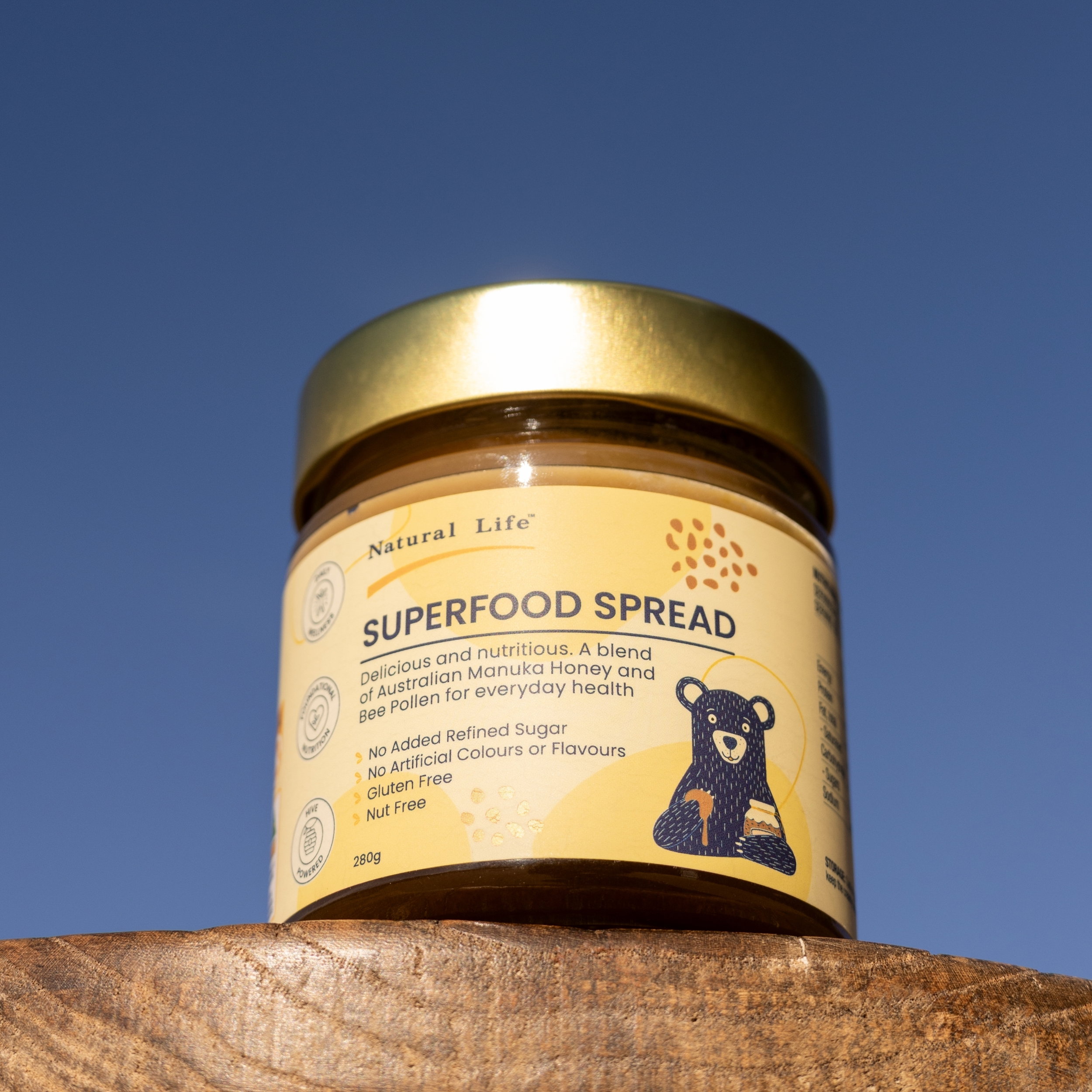Smiling girl holding a jar and spoonful of Superfood Spread as her mum looks on