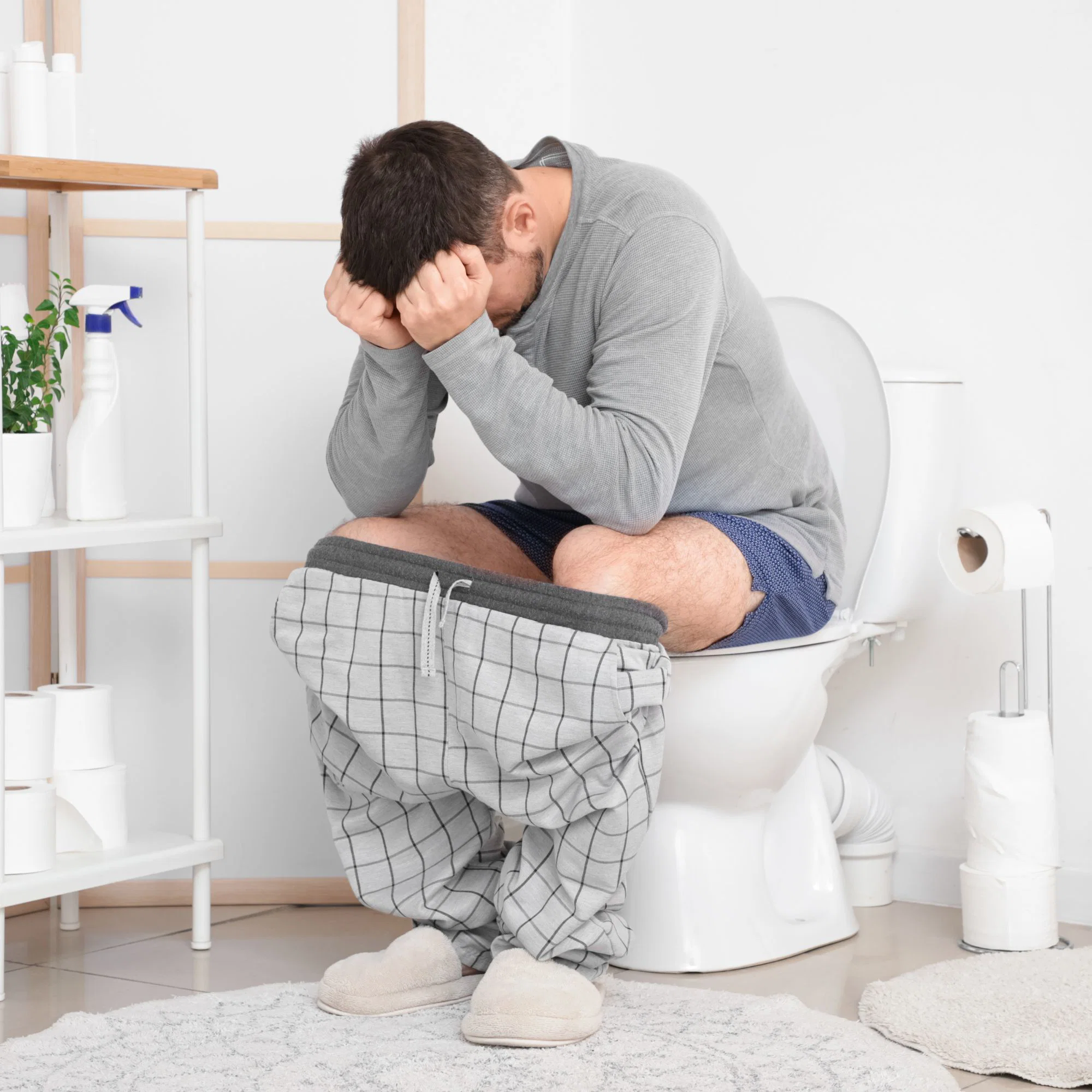 A frustrated man sitting on the toilet with his head in his hands