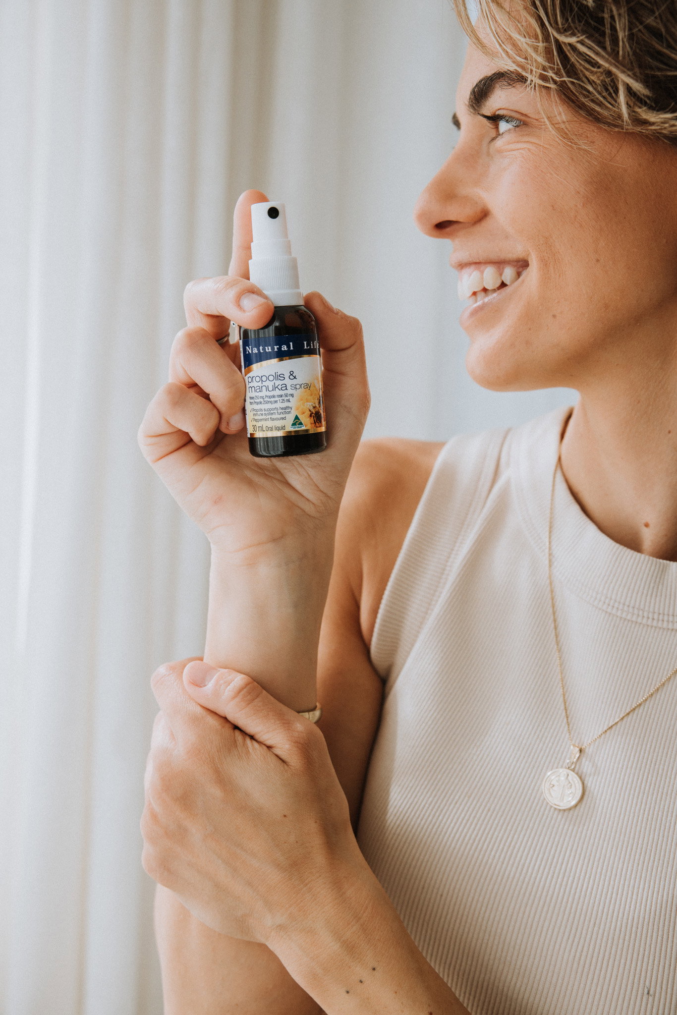 Woman holding the Propolis & Manuka Honey Spray in soft natural light
