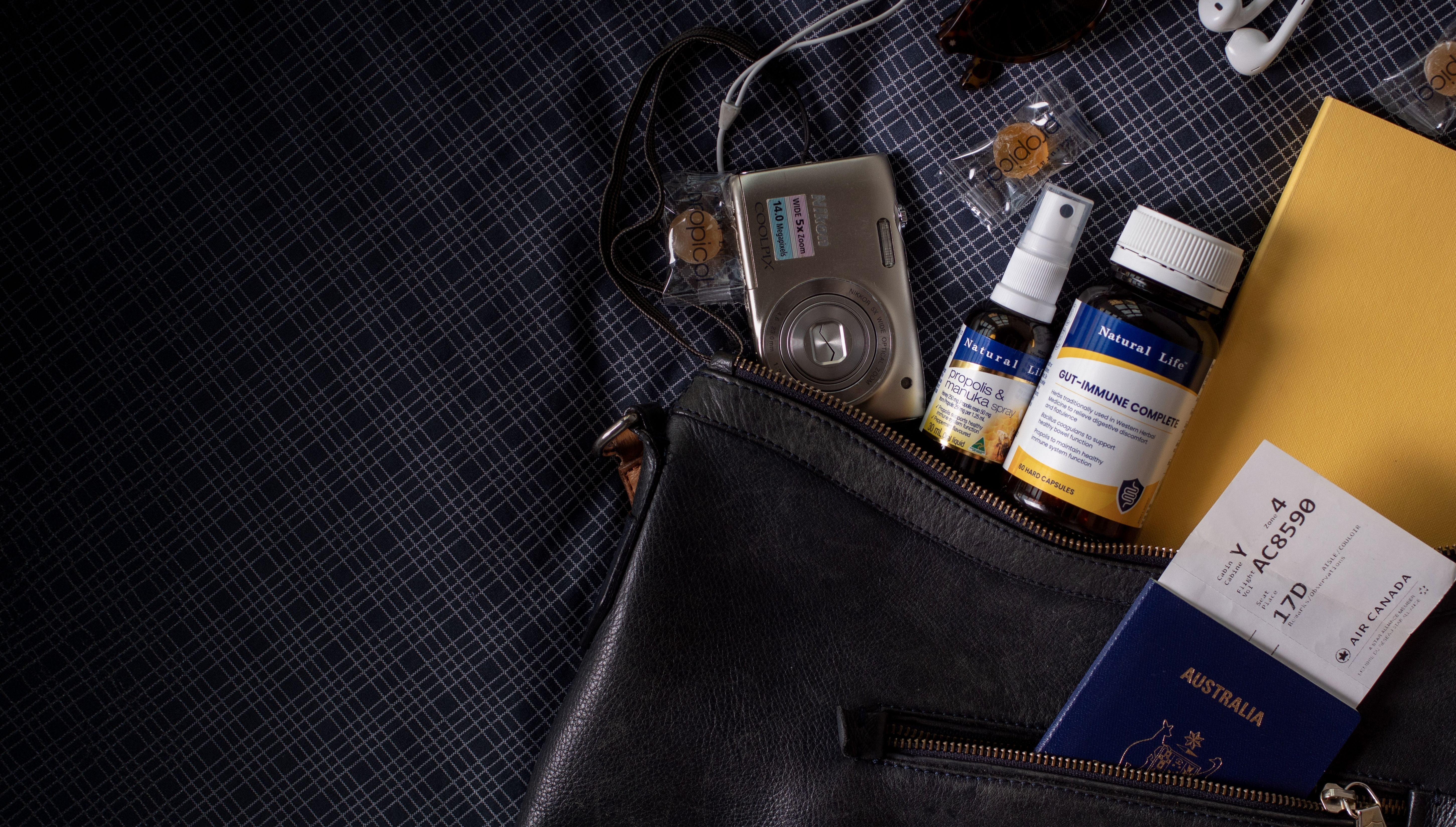 Natural Life Propolis & Manuka Honey Spray and Gut-Immune Complete packed in a travel bag with a passport and boarding pass