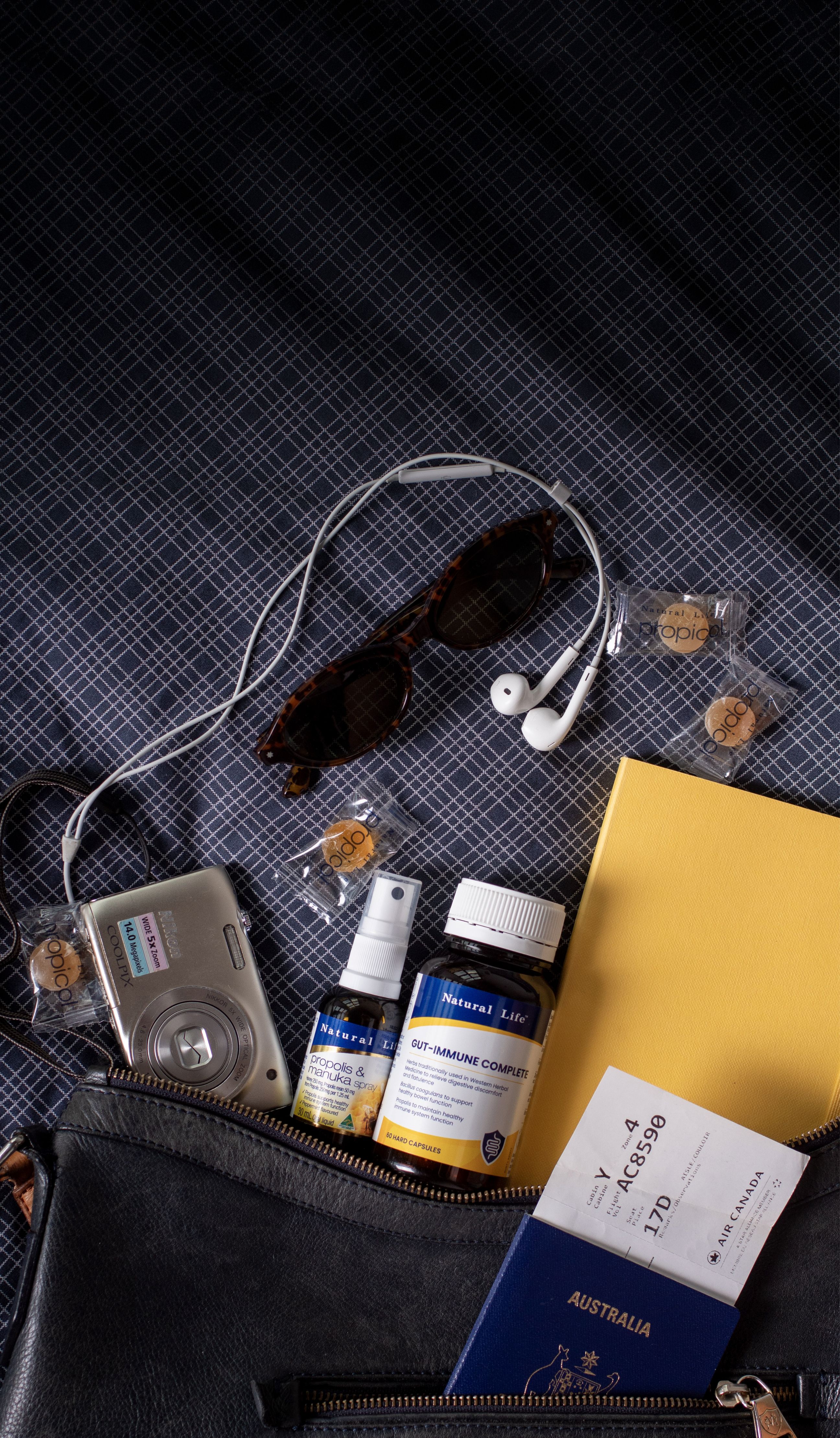 Natural Life Propolis & Manuka Honey Spray and Gut-Immune Complete packed in a travel bag with a passport and boarding pass