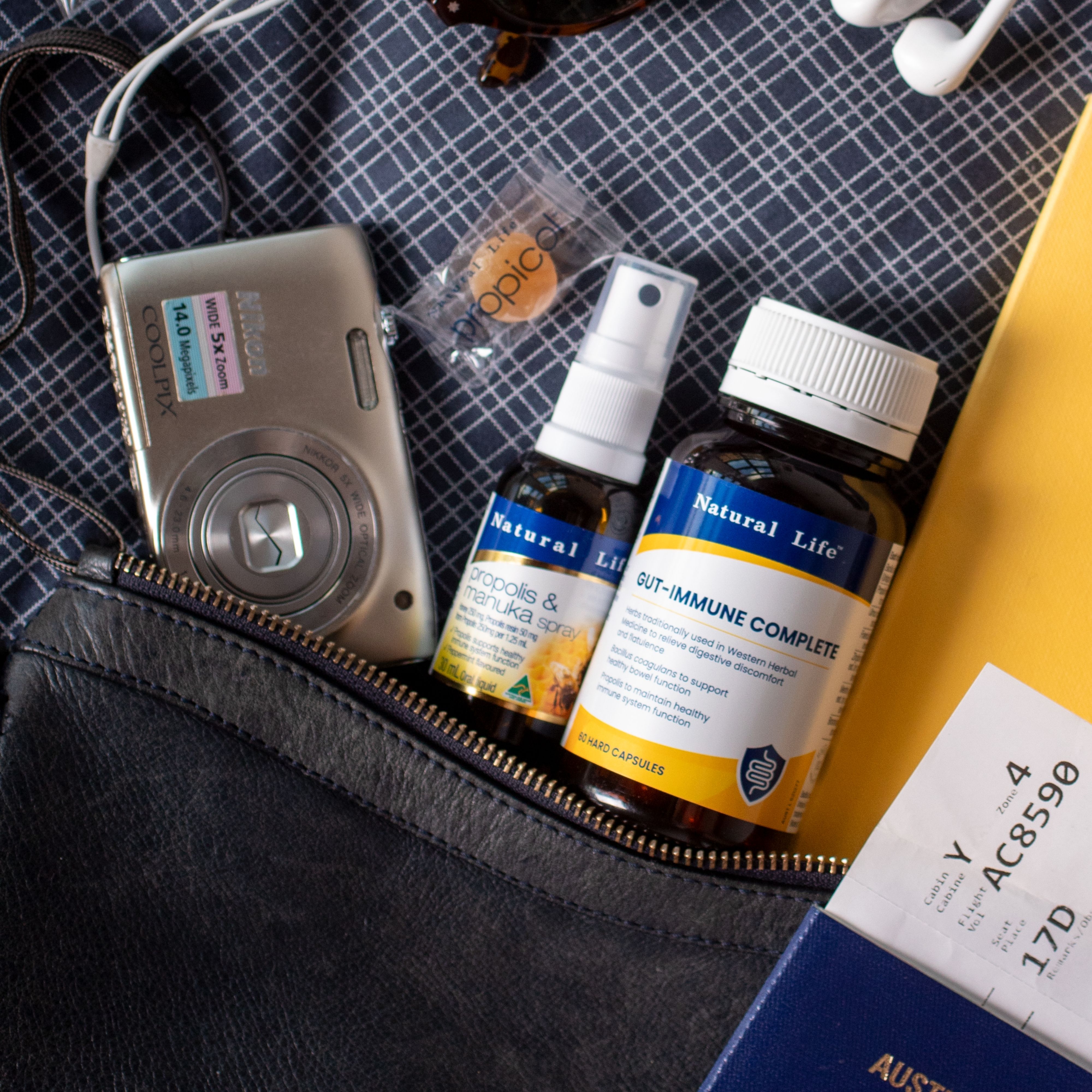 Natural Life propolis spray and Gut-Immune Complete packed in a travel bag with a camera, passport and boarding pass