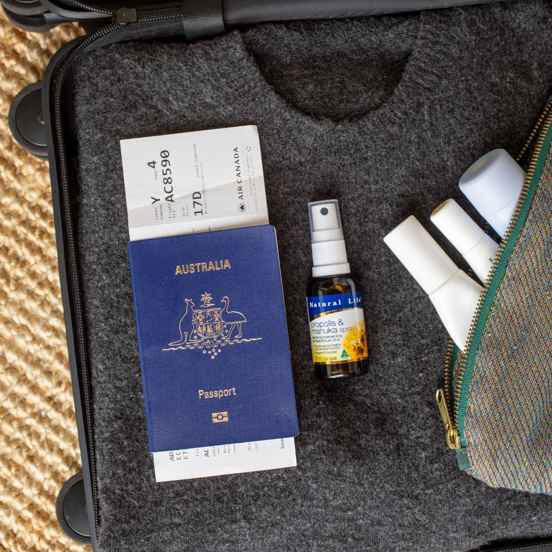 Natural Life Propolis & Manuka Honey Spray packed in a suitcase next to an Australian passport