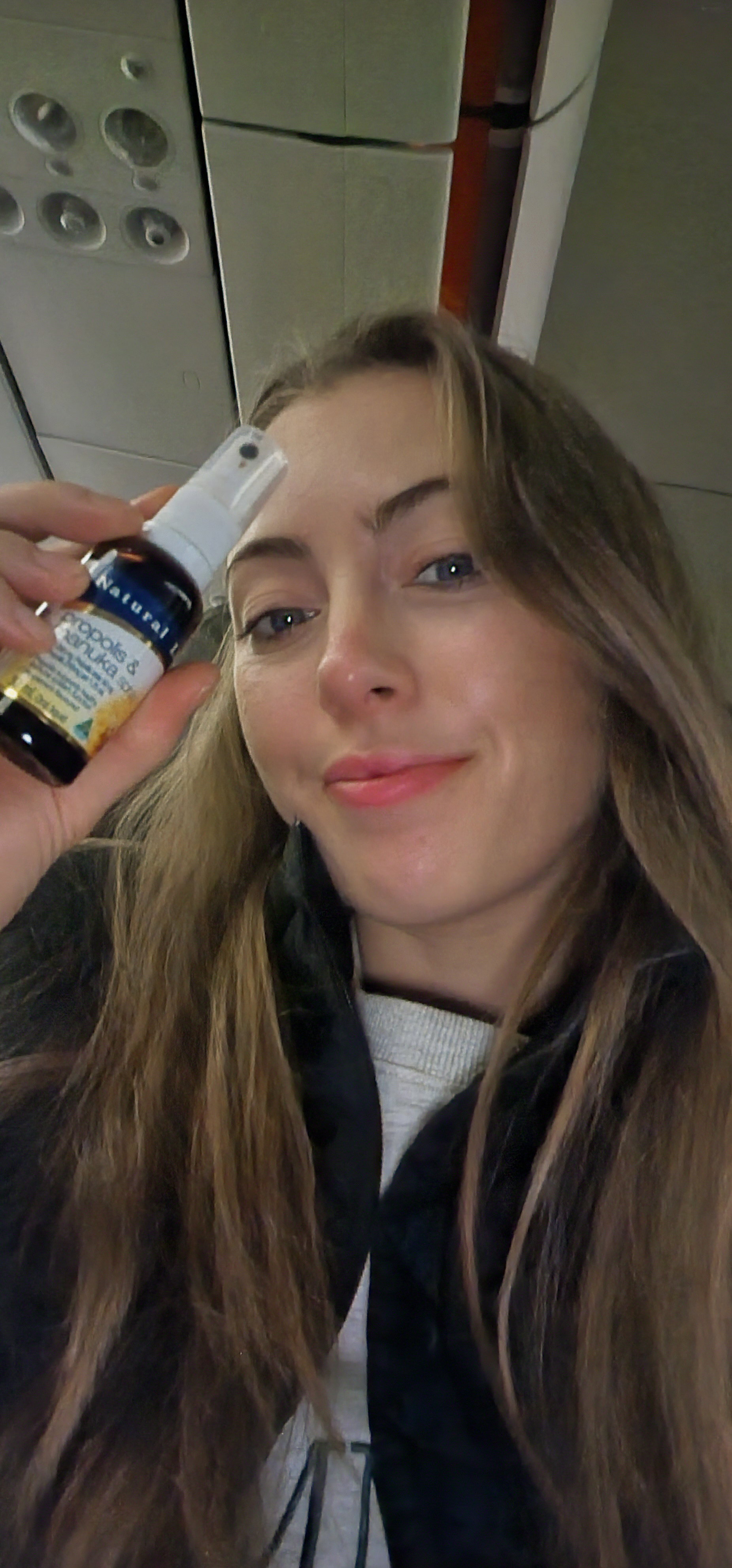 Woman in a plane window seat using Natural Life Propolis & Manuka Honey Spray