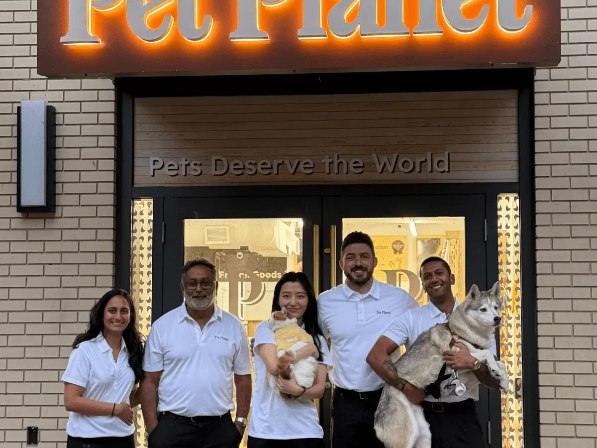 The Pet Planet Toronto team-members smiling together with their dogs in a sunlit-outdoor-park