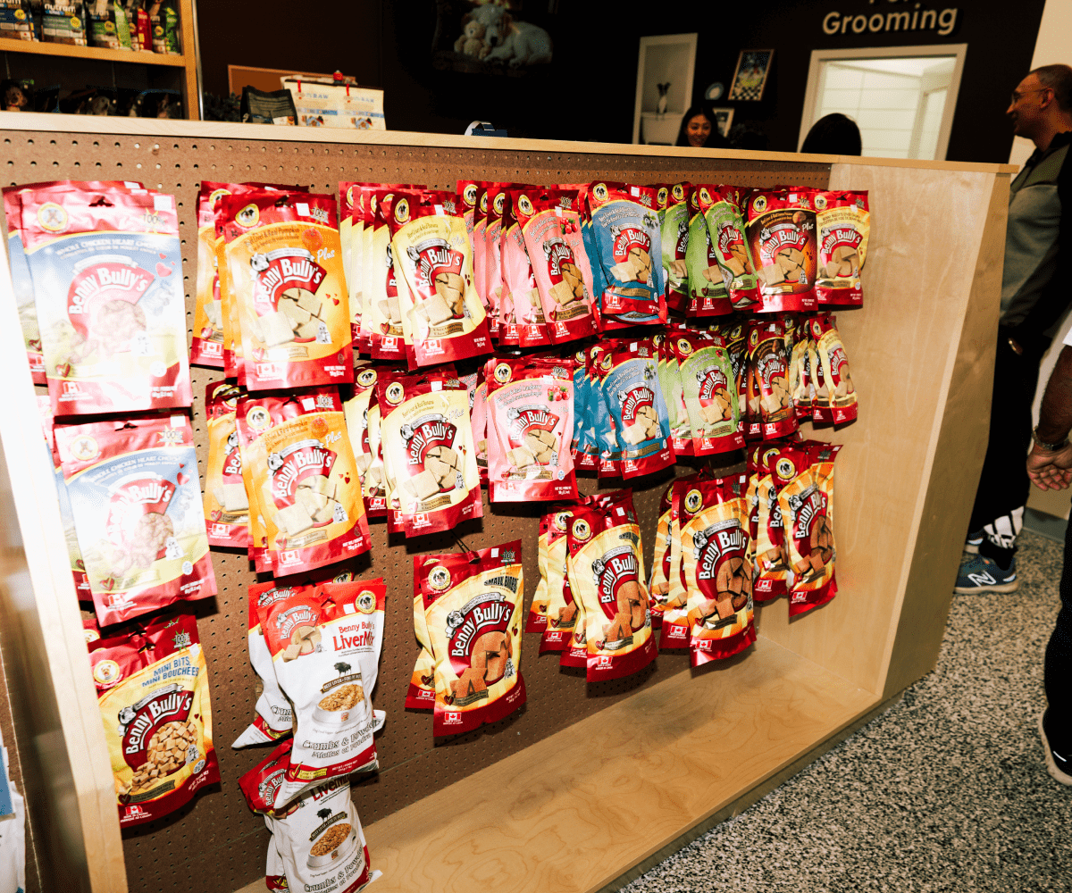 Various Benny Bully's dog treat packages hanging on a wooden pegboard display