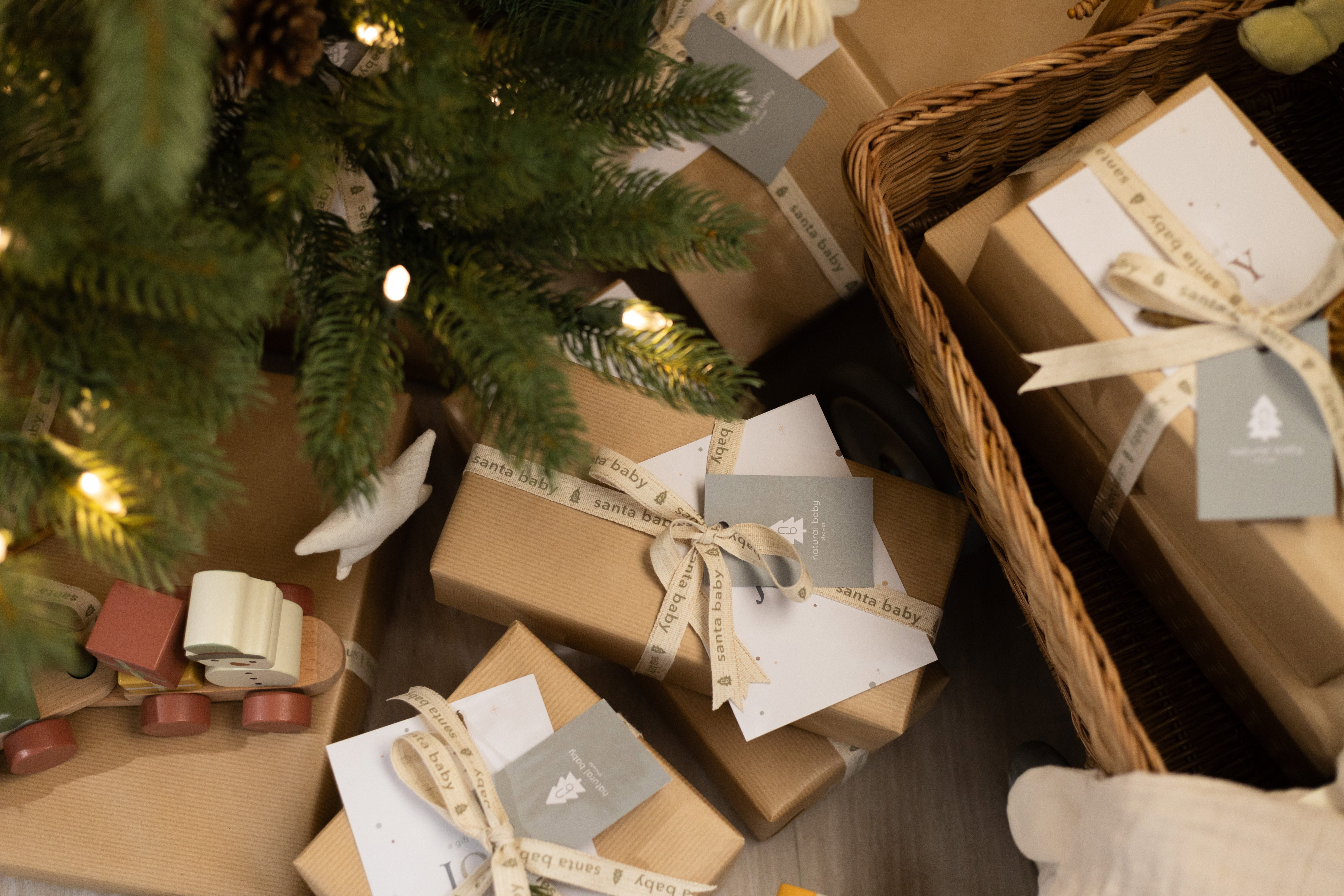 Kraft-paper wrapped Christmas gifts tied with cream ribbon under a lit Christmas tree
