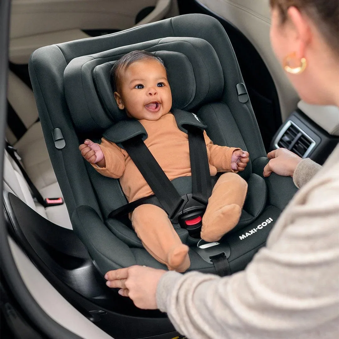 Parent securing a sleeping newborn into an infant car seat
