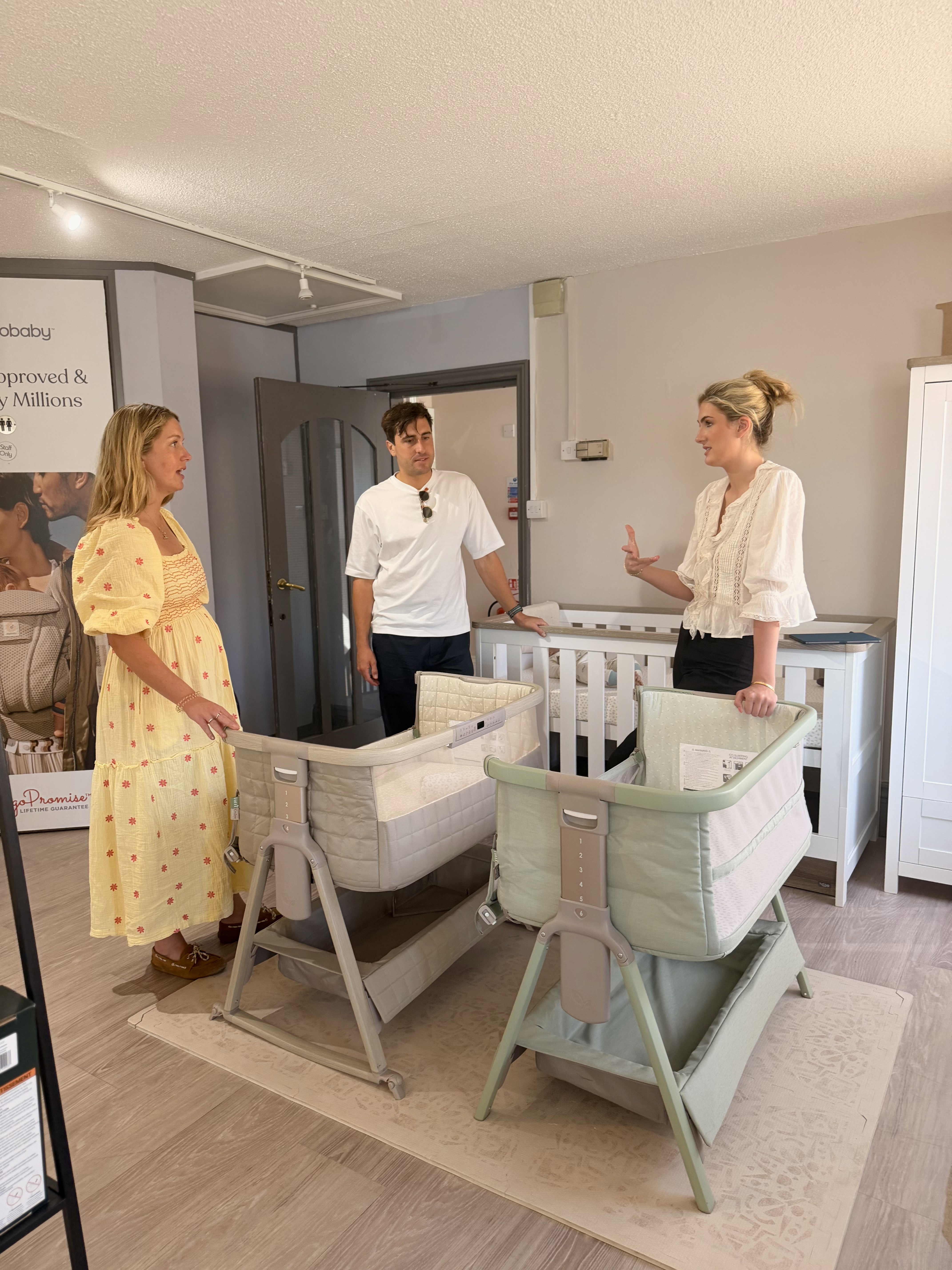 Expectant couple test-pushing a pushchair with carrycot around the store with a nursery expert