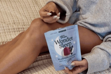 Woman in a cozy sweater holding a pouch of Wonder Sleep gummies