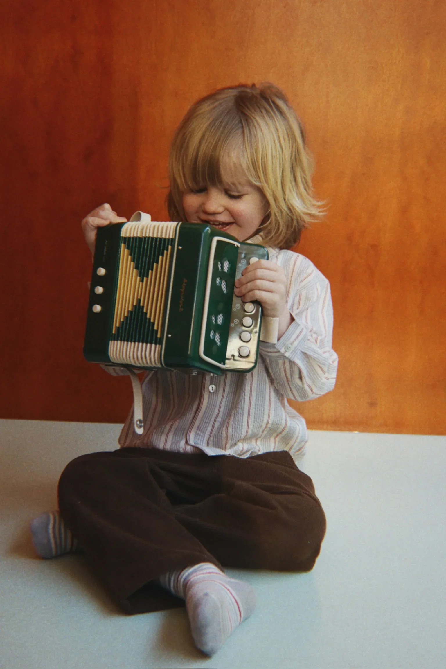 Jasper Isaac playing guitar and singing while a toddler dances on a picnic blanket in the park