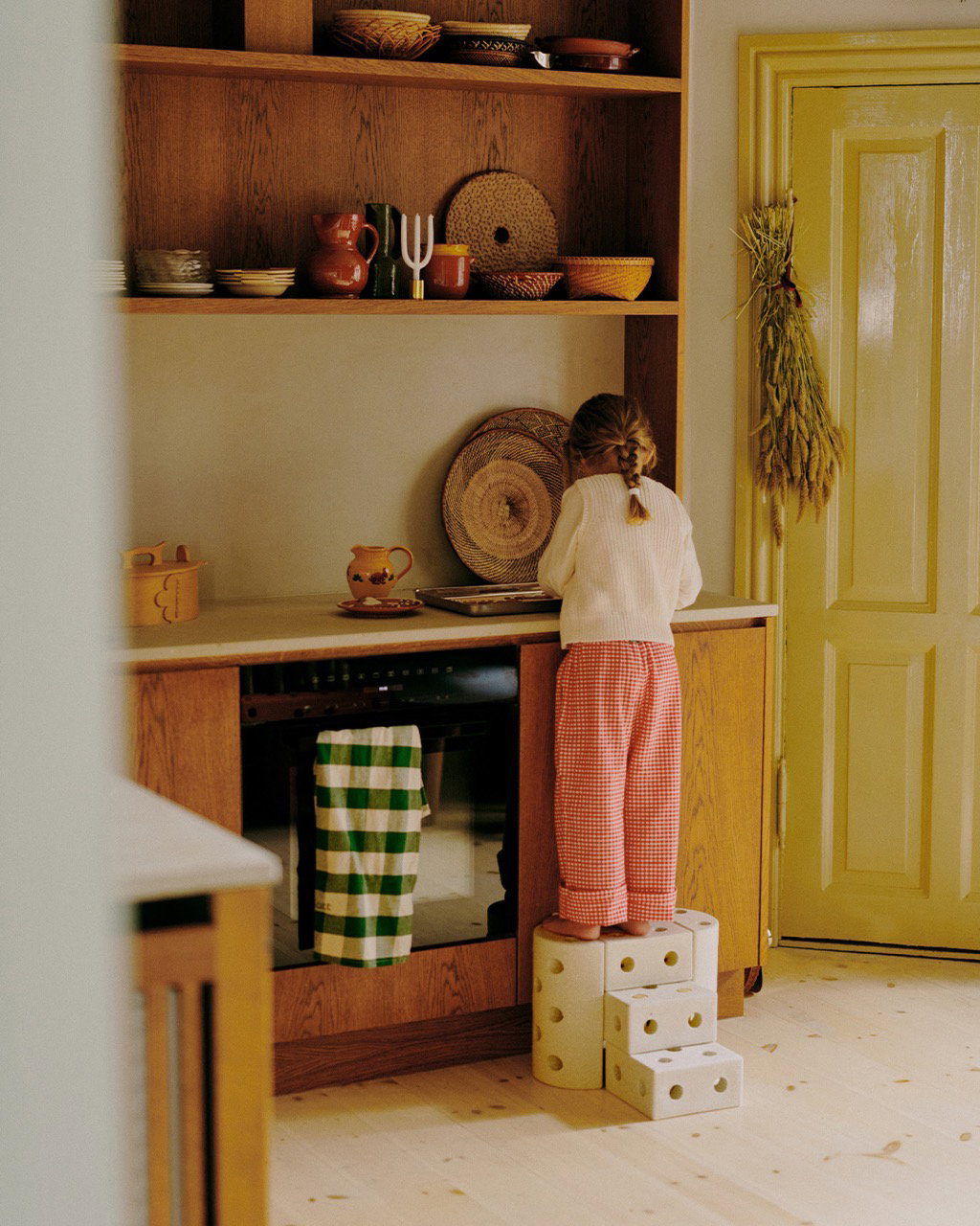 Child standing on stacked MODU foam blocks at a kitchen counter