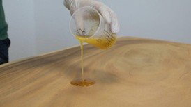 Pouring mixed hard wax oil onto the wooden tabletop