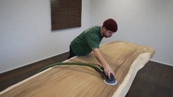 Sanding a solid wood tabletop with an orbital sander